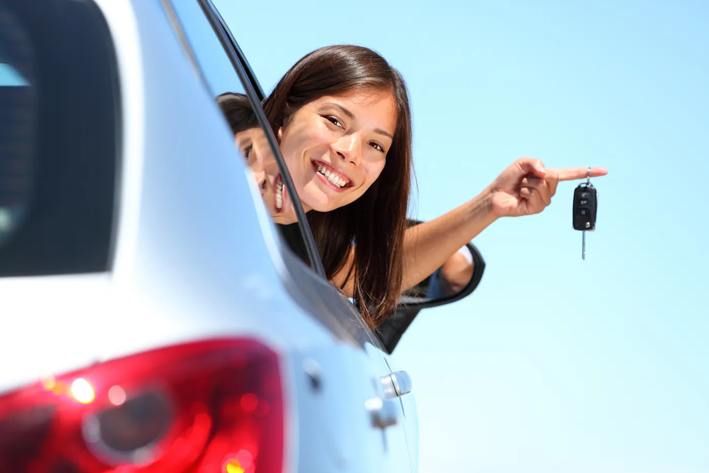 A driver leaning out of a car window, holding up a set of car keys