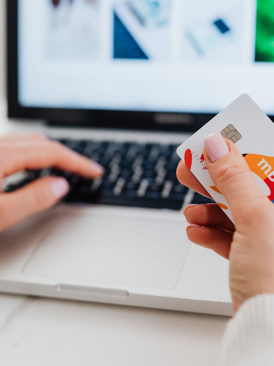 A shopper making an online purchase with a laptop and card